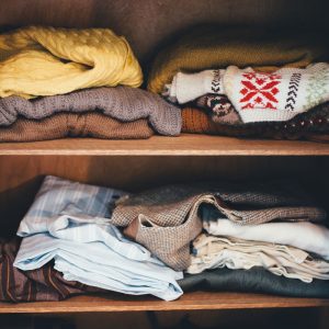 Photo of wooden shelves with multicolored knit sweaters on them