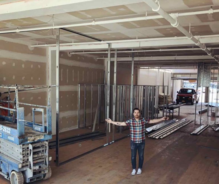 Interior of TGW Studio during the build out with a man standing in front with his arms out