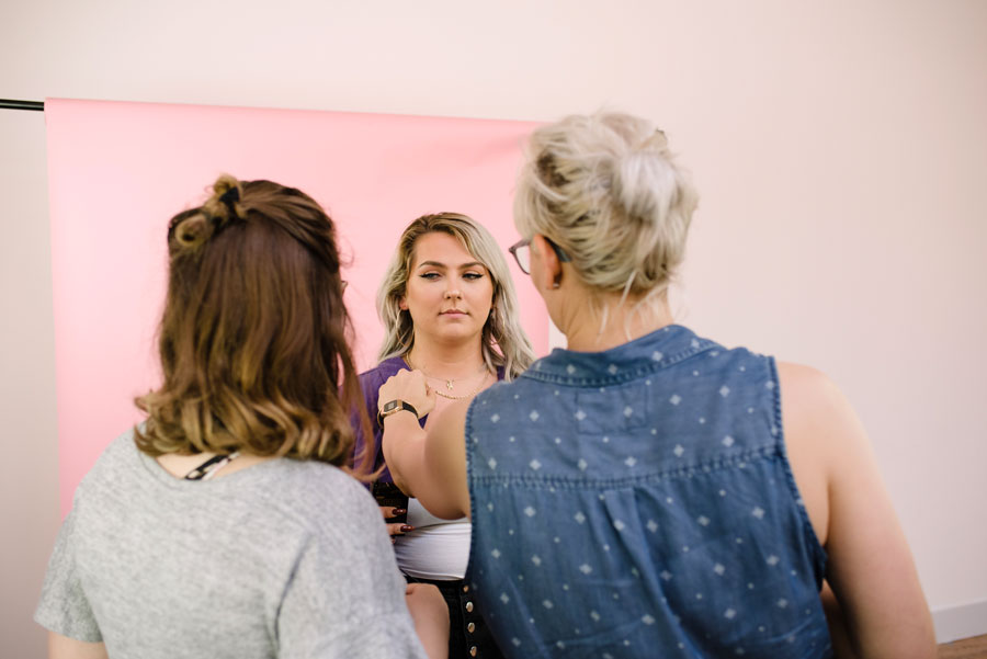 Photo of two people with backs to the camera adjusting the microphone on a third person with a pink backdrop as part of Trillium's Pillow Talk campaign