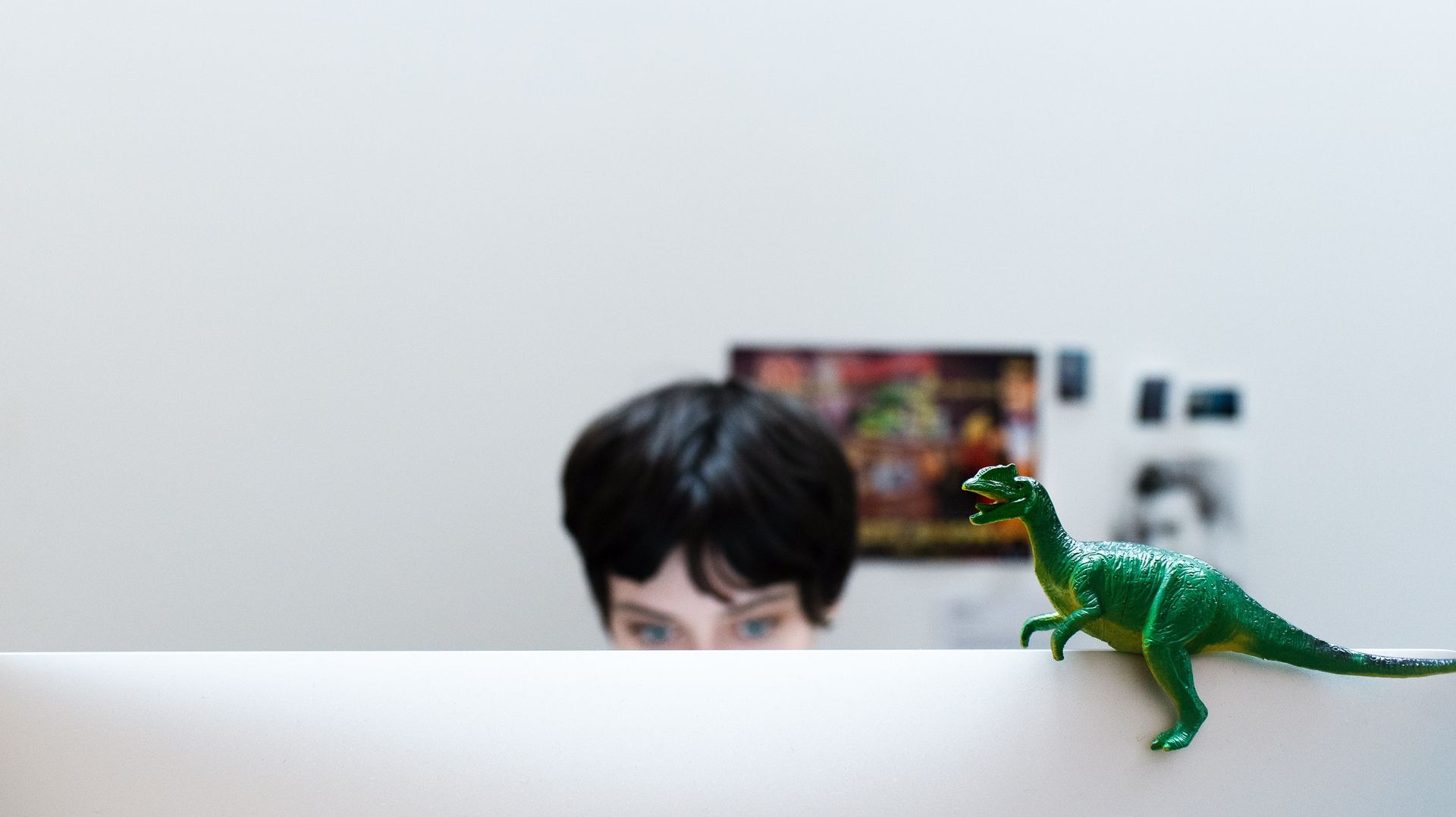 CB, our Creative Lead, sit behind her computer. A toy dinosaur is sitting atop the monitor