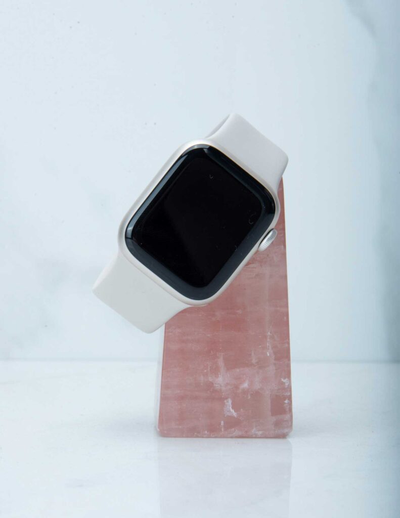 An apple watch resting on top of a rose quartz crystal