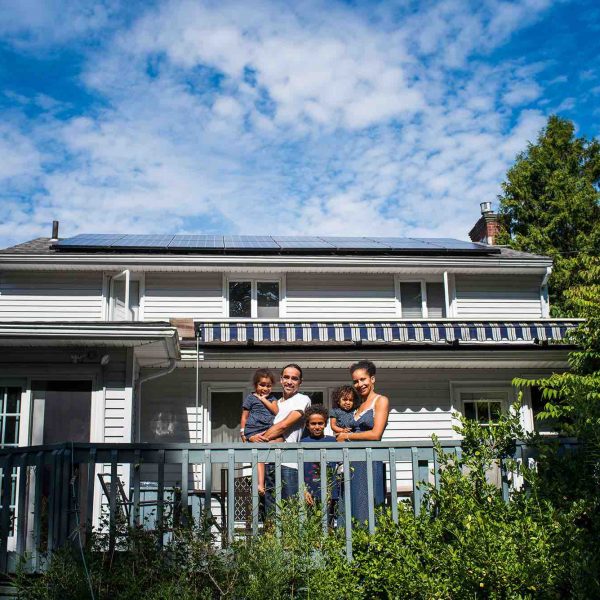 gss_paralax_banner_4_tgw_studio_case_studies Photo of a man, woman, and three children on a blue porch in front of their white house with solar panels on it, surrounded by green bushes and trees depicting social responsibility